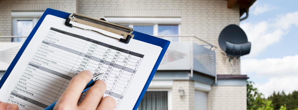 Home inspection document held in front with house in background