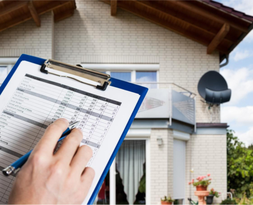 Home inspection document held in front with house in background