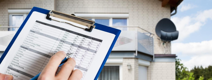 Home inspection document held in front with house in background