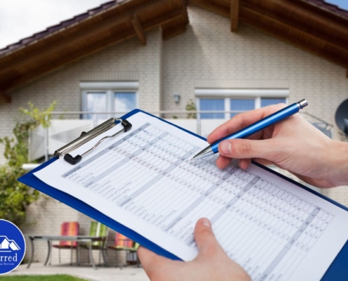 Home inspector filling out a detailed inspection checklist on a clipboard outside a residential property for a professional home inspection