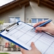 Home inspector filling out a detailed inspection checklist on a clipboard outside a residential property for a professional home inspection